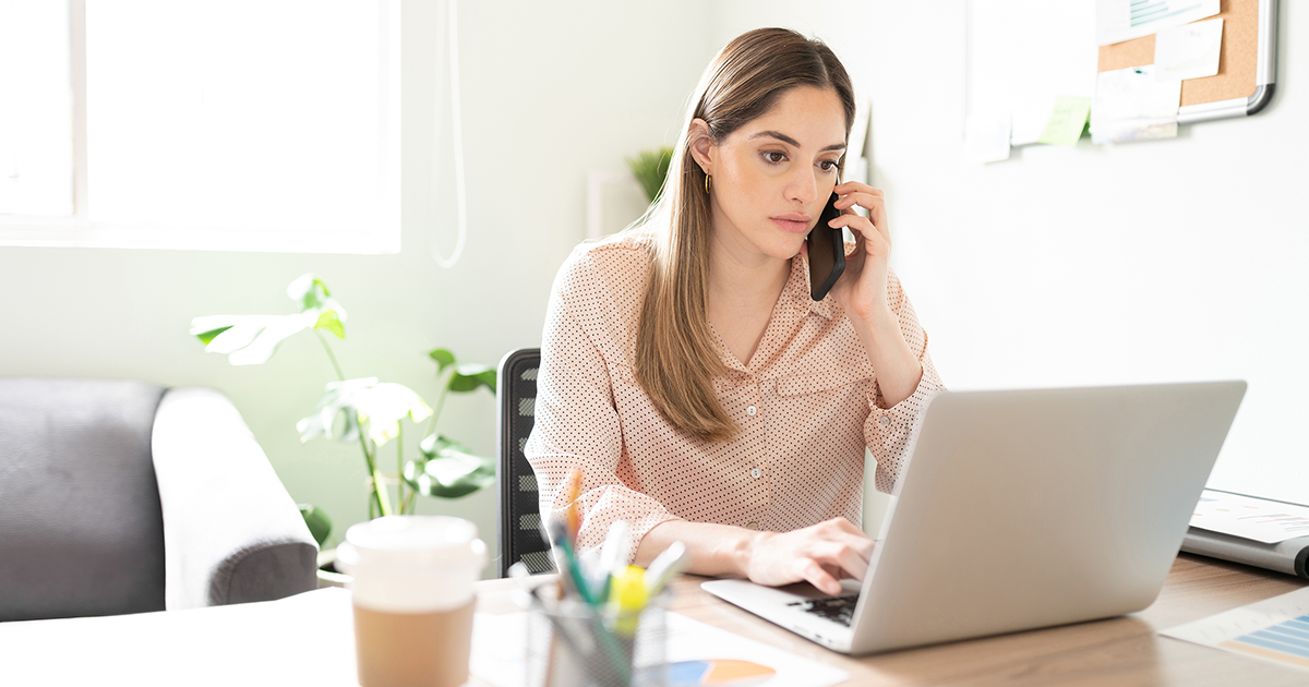 Businesswoman talking to a client on her phone and looking serious and worried while working in her office