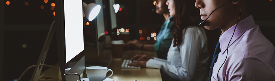 Employee working in front of computer at desk during night shift. 