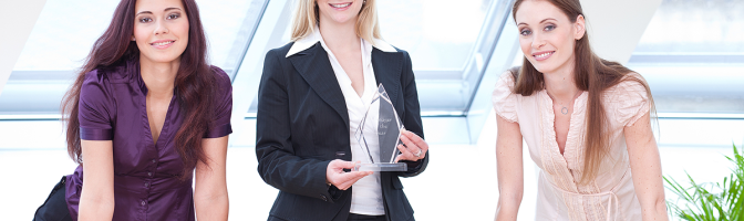 Three business women in conference room holding trophy award