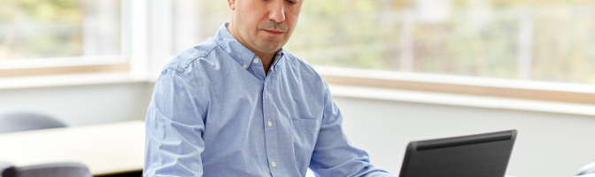 middle-aged man with calculator, papers and laptop computer working in office