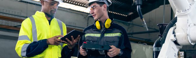 Two people talking while wearing safety paraphenelia.