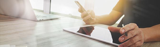 Man using mobile phone near laptop and tablet