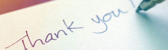 close up of someone writing thank you on a piece of paper