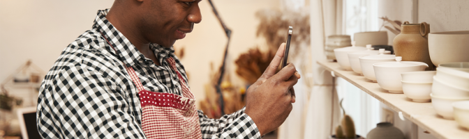 Male ceramist taking photos of earthenware products for sale