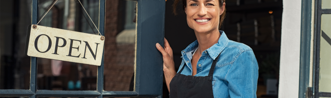 Portrait of a happy waitress standing at restaurant entrance.
