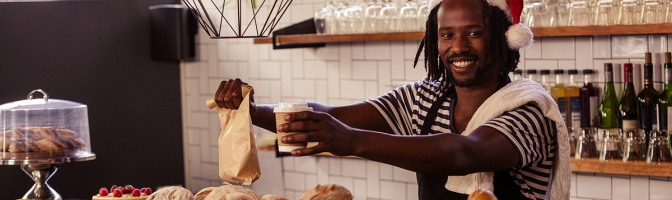 Smiling employee serving take away order at coffee shop