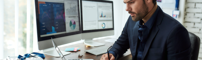 Young focused businessman or financial analyst sitting at his workplace in the office and working on laptop. 