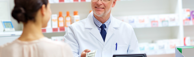 female customer paying money to senior pharmacist at pharmacy cash register