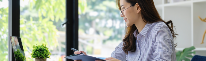 small business owner working in home office working on computer and using paper documents