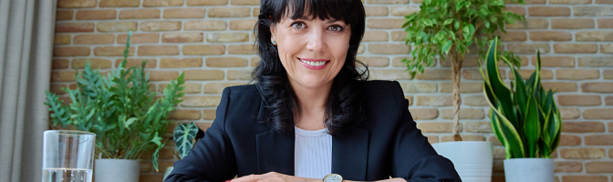 Businesswoman sitting at conference room table smiling at camera. 