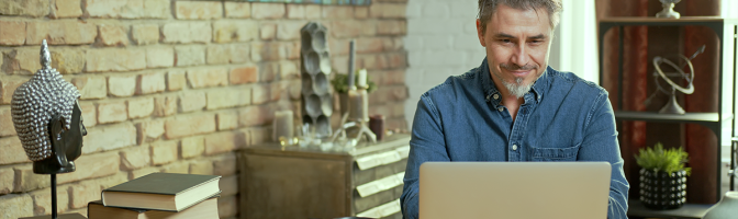 Mature man working on laptop computer in office, thinking, looking busy