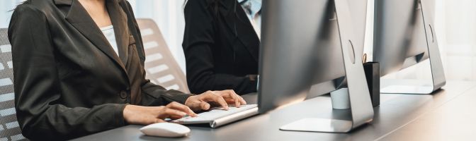 work computers lined up with woman in blazer typing on one