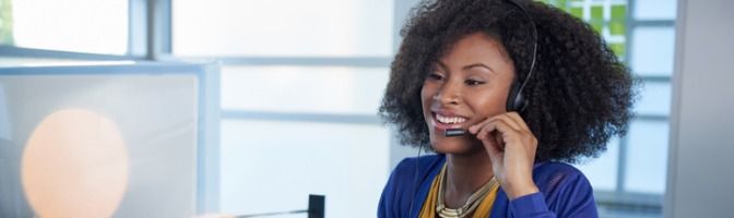 Call center tech talking through a headset in front of a computer