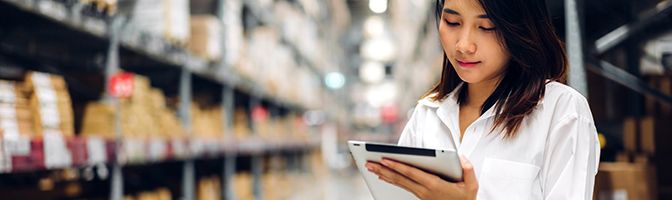 Small Business owner checking supplies using a tablet in a warehouse.