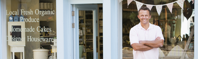 Man stating in front of small business storefront. 