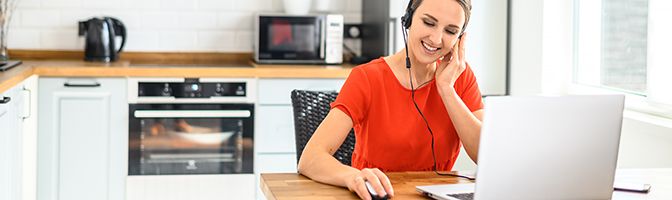 Remote employee wearing a headset working in front of a laptop.