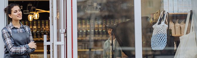 Female Entrepreneur stands by the door of her coffee shop.