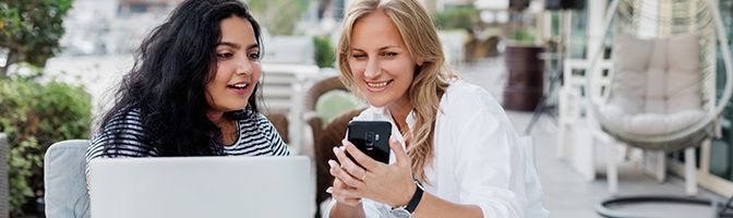 Two business owners take a break from work to look at a mobile device.