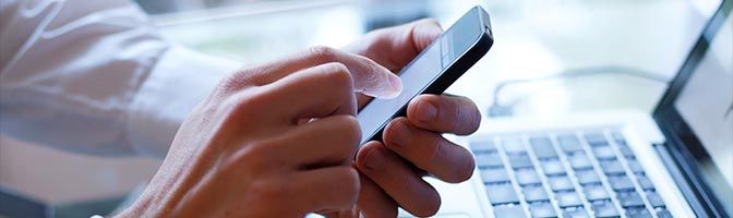 Man using mobile phone near laptop