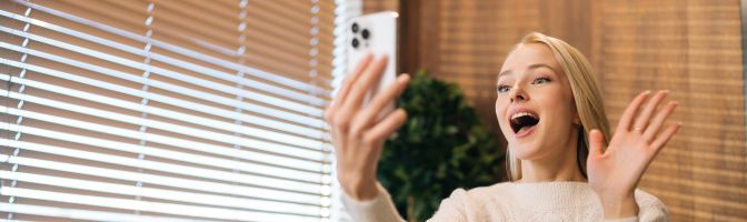 woman waving to video on mobile phone