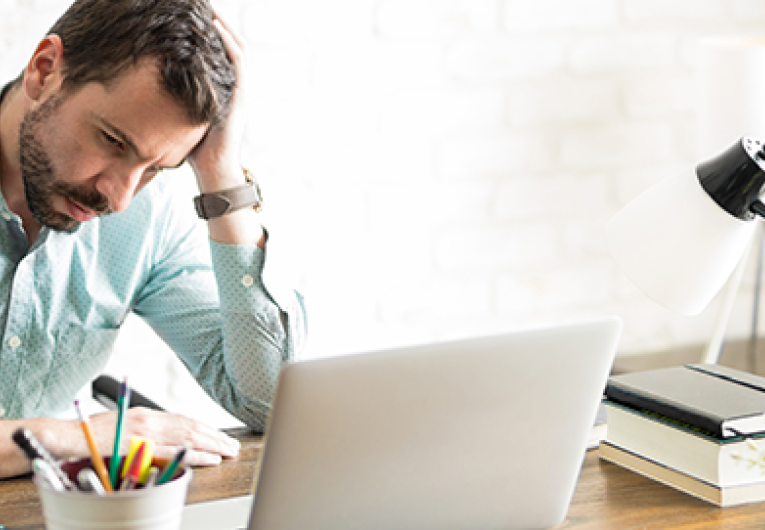 Frustrated business owner sitting with a hand on his head and a worried look