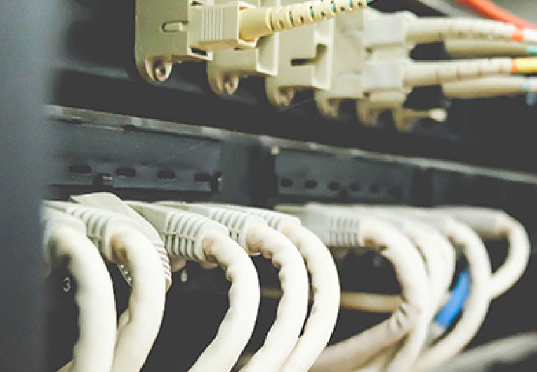 Image of fiber and Ethernet routers mounted on a rack in a cabinet