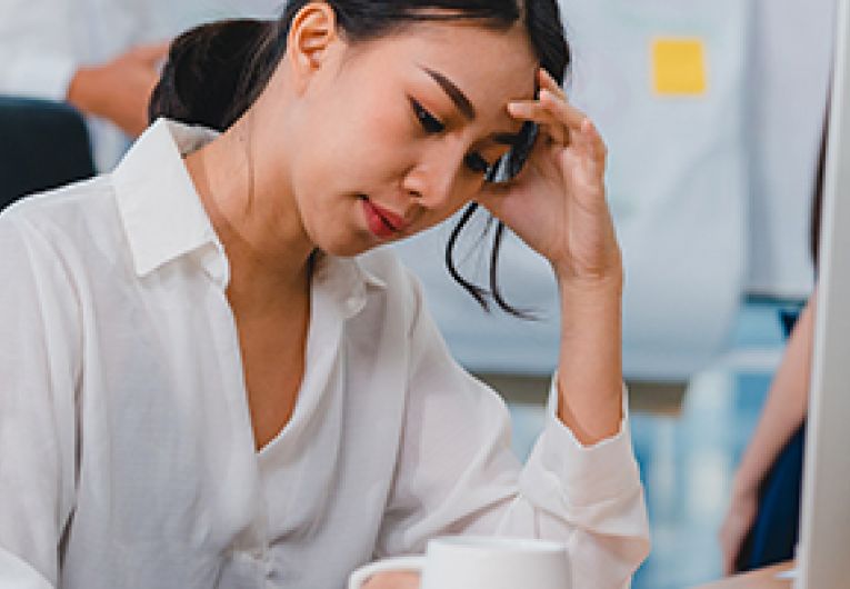 Business woman looks frustrated while sitting in front of a computer.