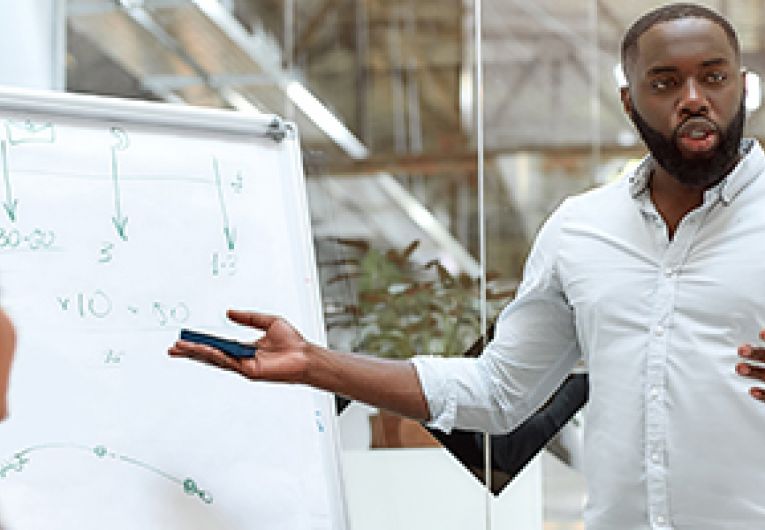 Small business owner stands while giving a presentation to their staff members.