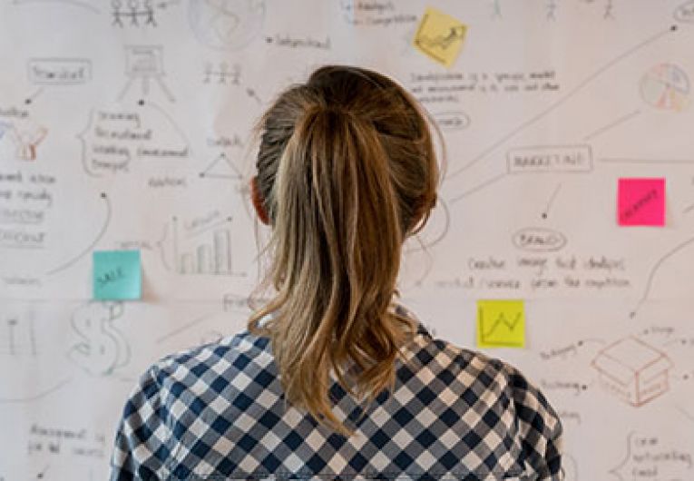 woman looking at board with post it notes