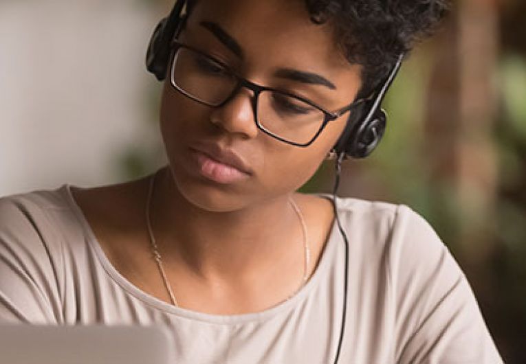 woman using laptop while wearing headphones