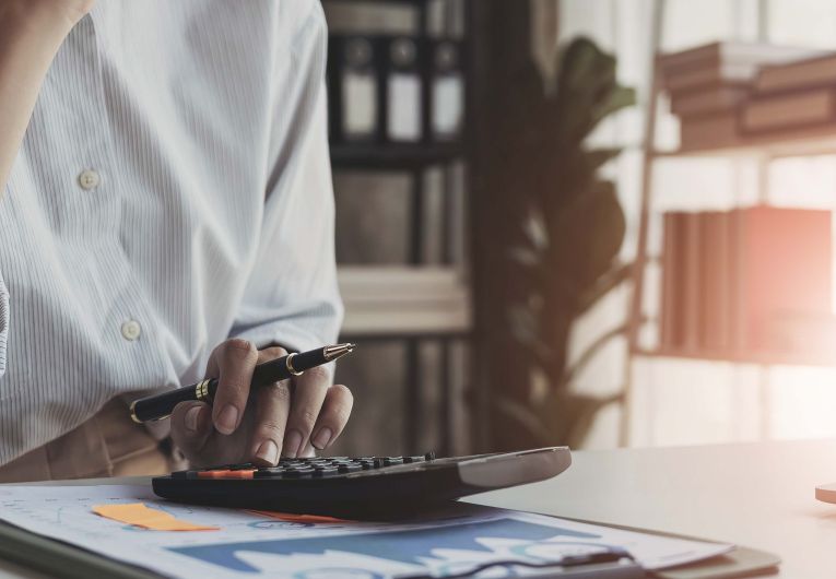 A person uses a calculator while sitting at a desk.