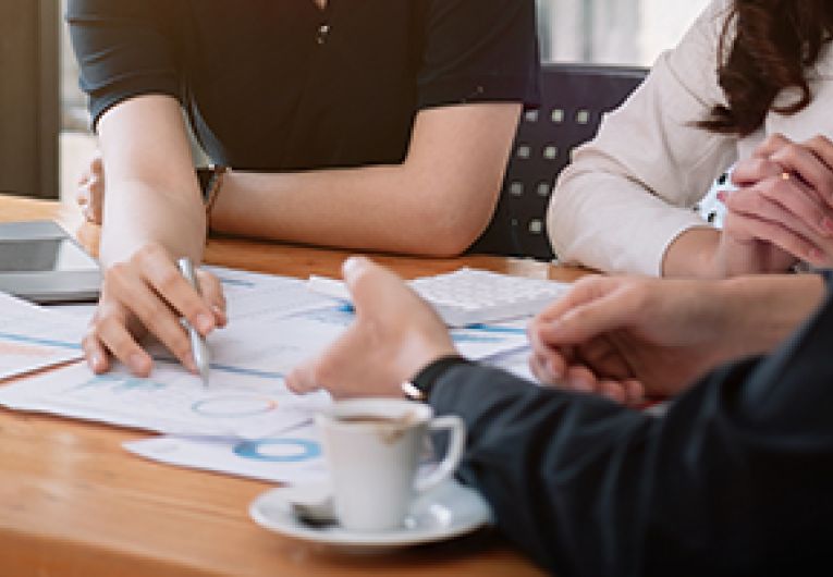 Small business owners go over financing strategies during a discussing while sitting around a table.