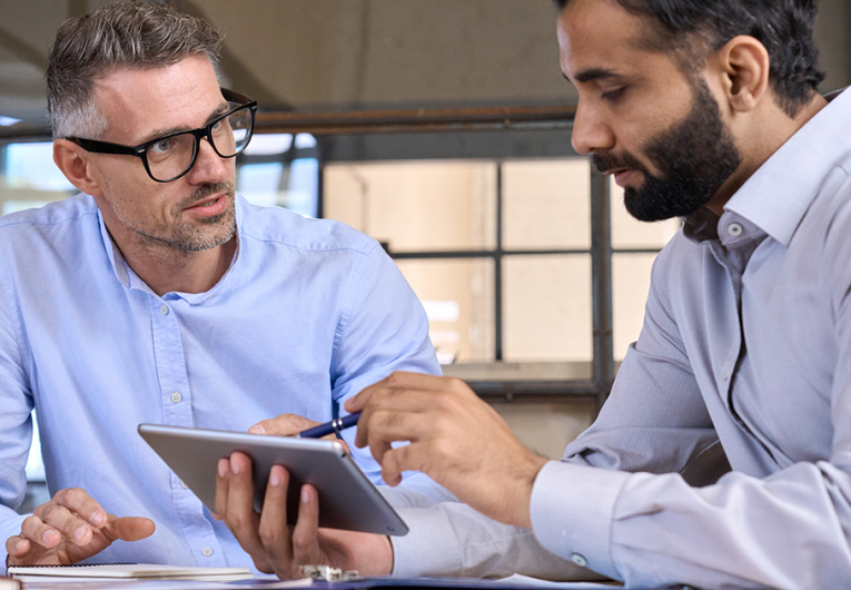 Two businessmen discussing financial report planning sitting at table in office.