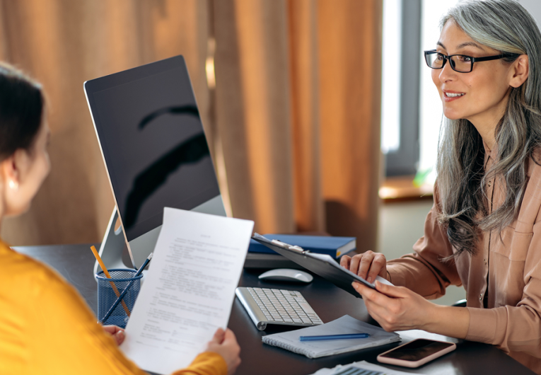 A Mature gray-haired woman, employer, meeting with female employee, sitting in office at the workplace.