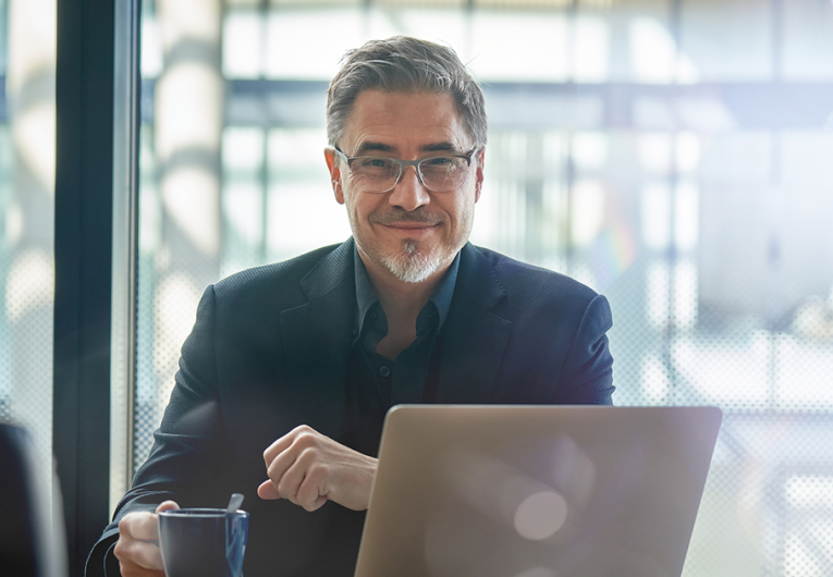 Mature businessman sitting in in office working with laptop computer.