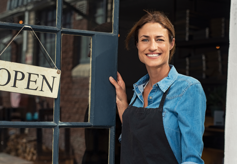 Portrait of a happy waitress standing at restaurant entrance.