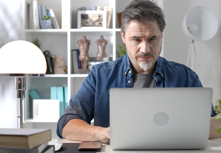 Man in casual sitting at desk using laptop computer, business manager online in home office.