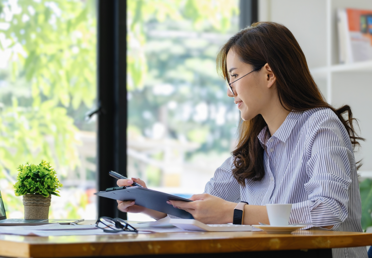 small business owner working in home office working on computer and using paper documents