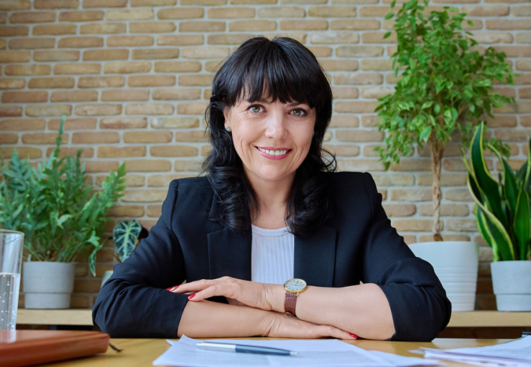 Businesswoman sitting at conference room table smiling at camera. 