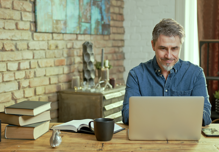 Mature man working on laptop computer in office, thinking, looking busy