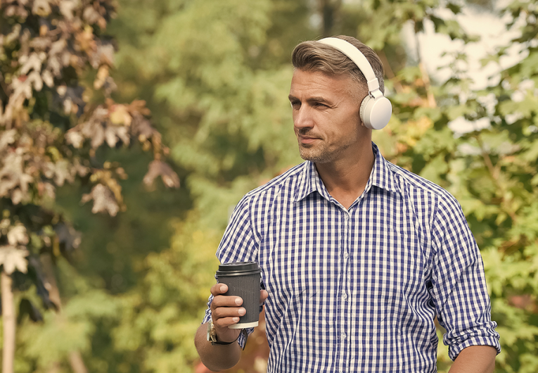 gentleman sitting outside listening to podcast while drink coffee