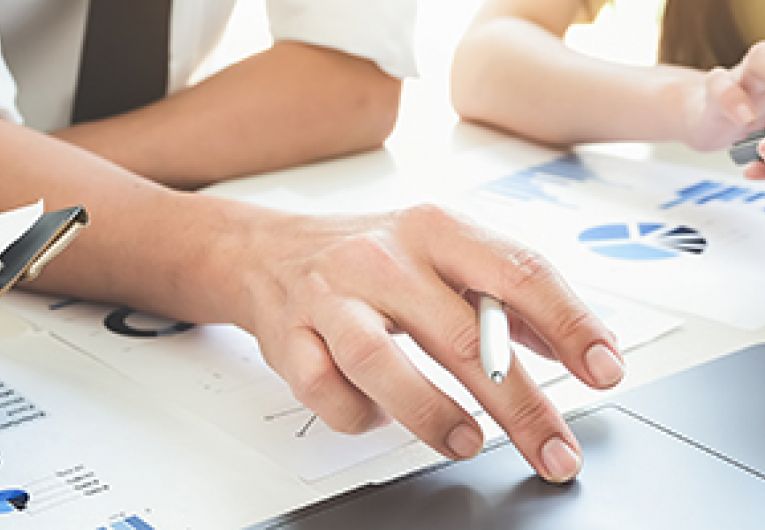 A small business team meet to discuss strategy while reviewing charts in front of a laptop..