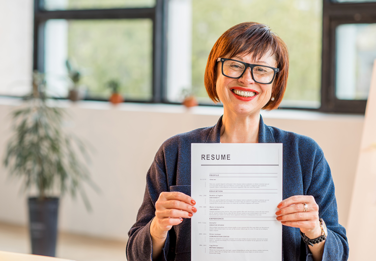 Elegant older woman holding resume document sitting in office