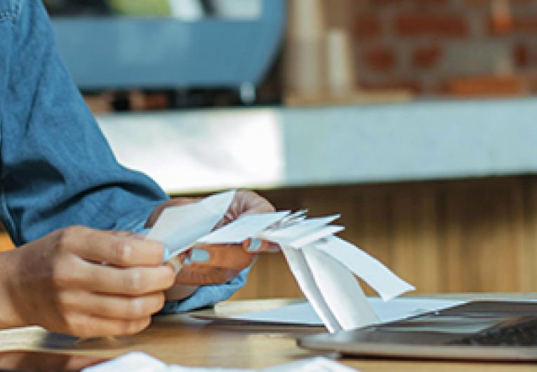 Small business owner holding receipts while sitting in front of a laptop.