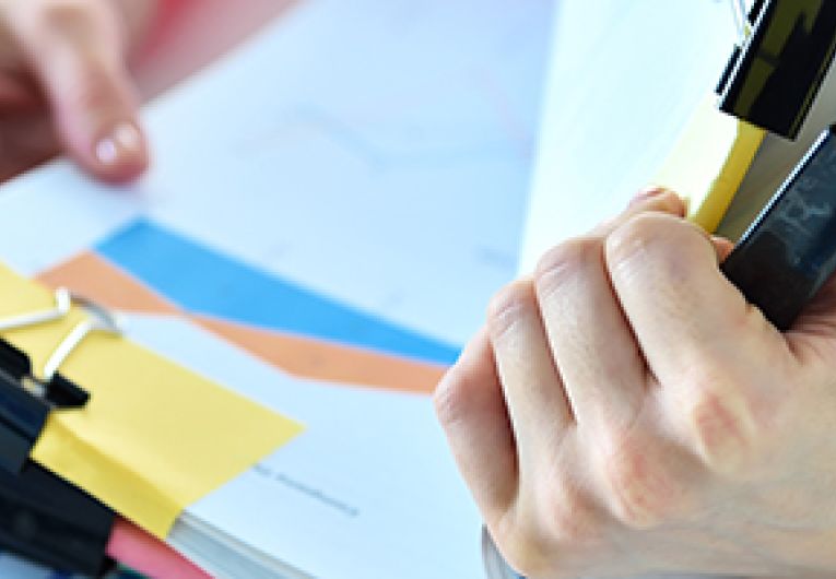 Closeup of a person's hand holding a large stack of paperwork.