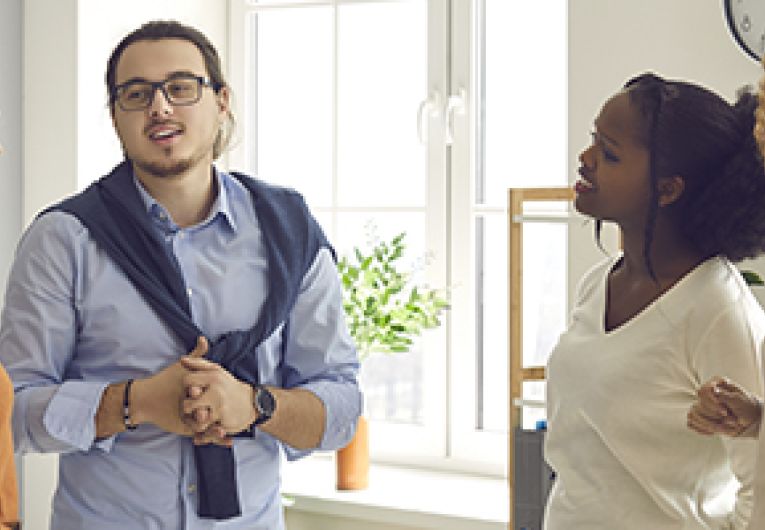 A group of four people stand in a circle while having a discussion.