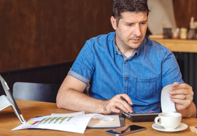 Male restaurant owner sitting at table while reviewing budget.