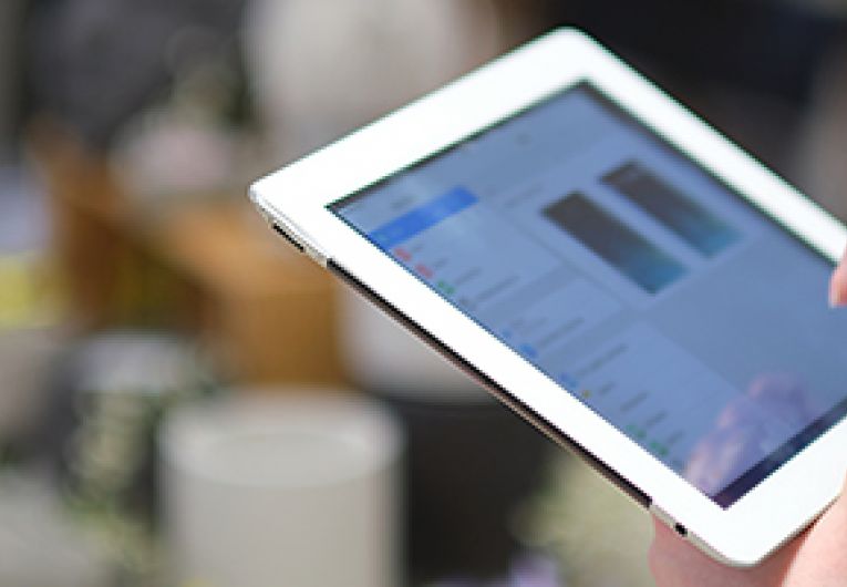 Closeup of a business owner scrolling through information on a tablet device.