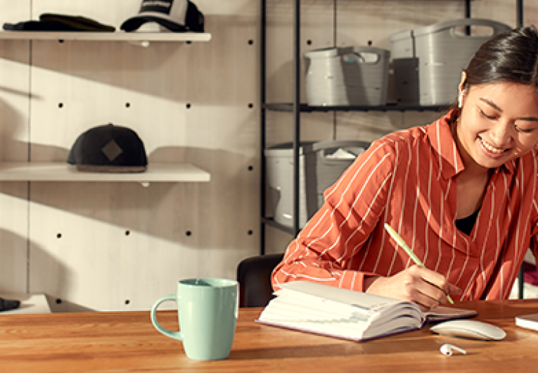 Female business owner making notes, receiving online orders while sitting in the office.