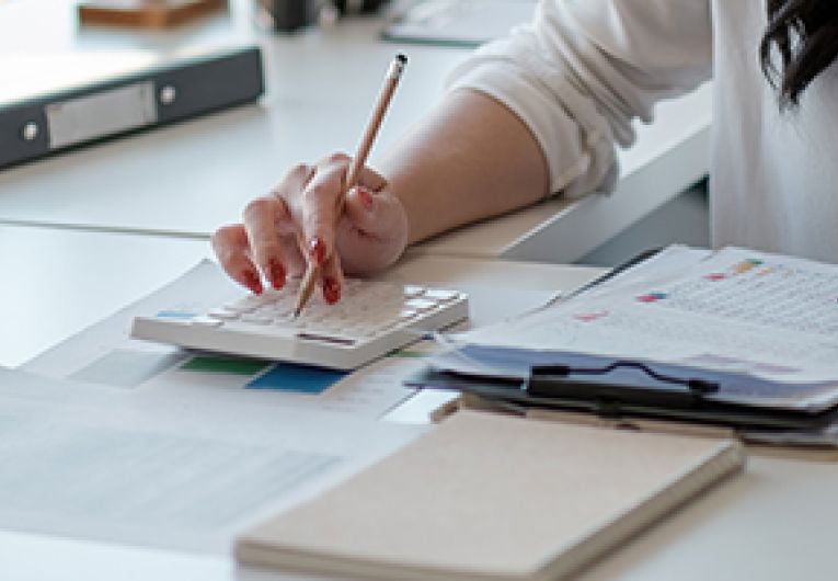 A person writing in a notebook at a desk.